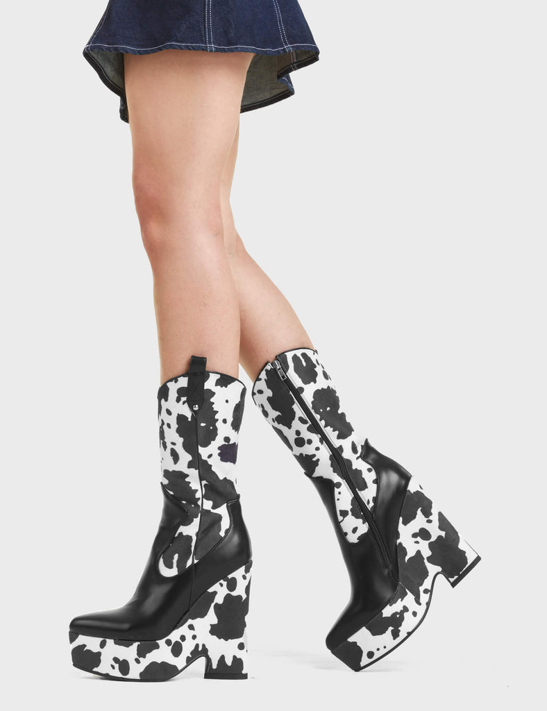 Here We Are Chunky Platform Calf Boots feature a cow print design, and features a heart shaped heel.