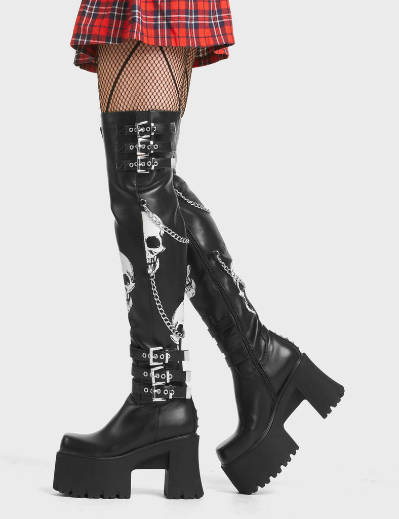 Nemesis Platform Thigh High Boots in Black. Feature skull print and adjustable straps.